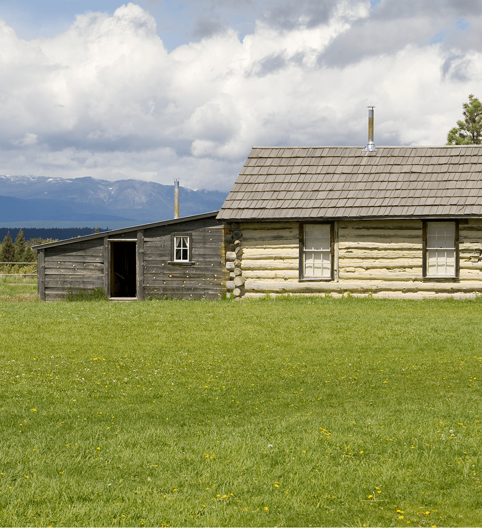 Log cabin with green lawn and mountains