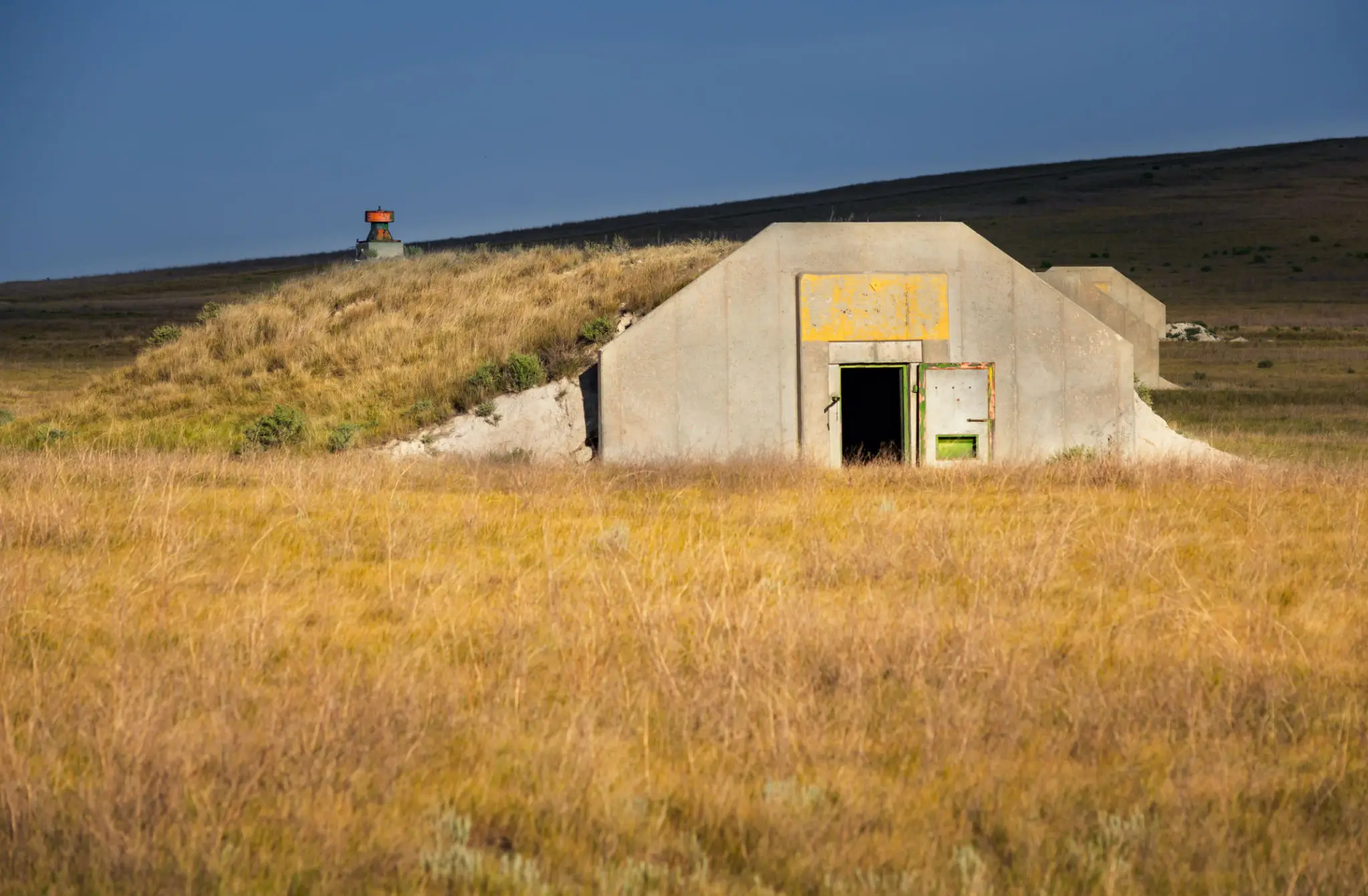 Concrete bunker entrance in golden grassy field